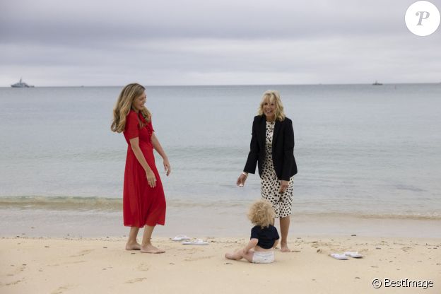 Carrie Johnson s'entretient avec la Première Dame des États-Unis, Jill Biden, lors du sommet des dirigeants du G7 à Carbis Bay, Royaume Uni, le 10 juin 2021, alors que Wilfred Johnson est assis sur la plage.