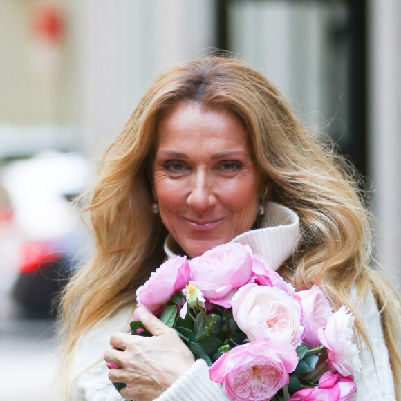 Celine Dion rayonnante et très souriante dans un ensemble pull écru et jupe bouffante fleurie salue ses fans à la sortie de son hôtel à New York.