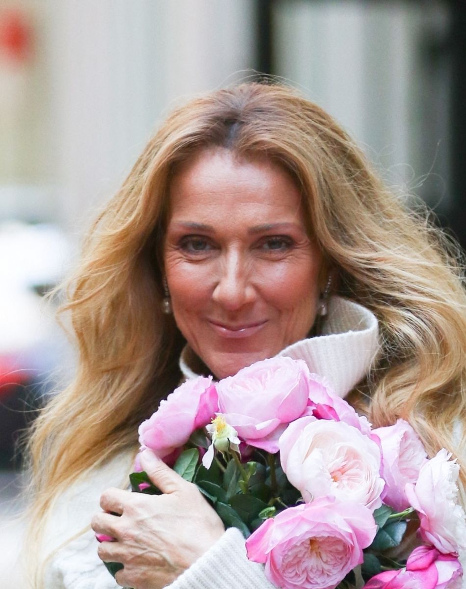 Celine Dion rayonnante et très souriante dans un ensemble pull écru et jupe bouffante fleurie salue ses fans à la sortie de son hôtel à New York.