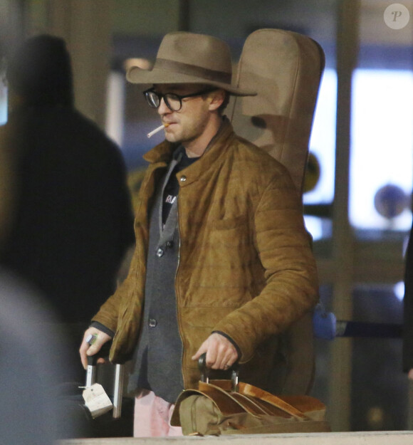 Tom Felton arrive à l'aéroport de Vancouver le 9 janvier 2017. Il porte une guitare sur le dos et une paire de jean rose 