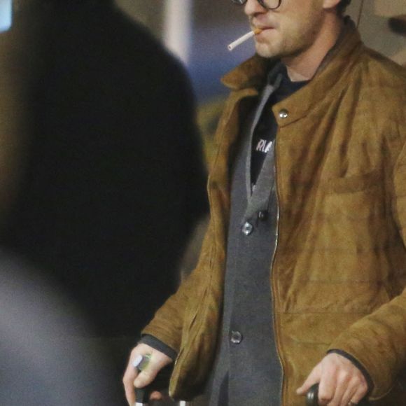 Tom Felton arrive à l'aéroport de Vancouver le 9 janvier 2017. Il porte une guitare sur le dos et une paire de jean rose 