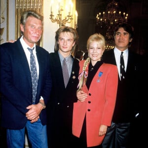 Sylvie Vartan reçoit la médaille de l'Ordre National du Mérite en présence de son mari Tony Scotti, Johnny Hallyday et leur fils David Hallyday, en 1987. 