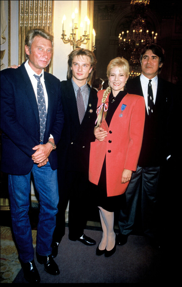 Sylvie Vartan reçoit la médaille de l'Ordre National du Mérite en présence de son mari Tony Scotti, Johnny Hallyday et leur fils David Hallyday, en 1987. 