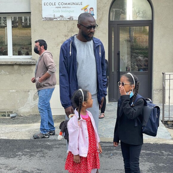 Thomas Ngijol et ses filles Angelina et Carmen devant la porte de leur école bilingue, en Corse.