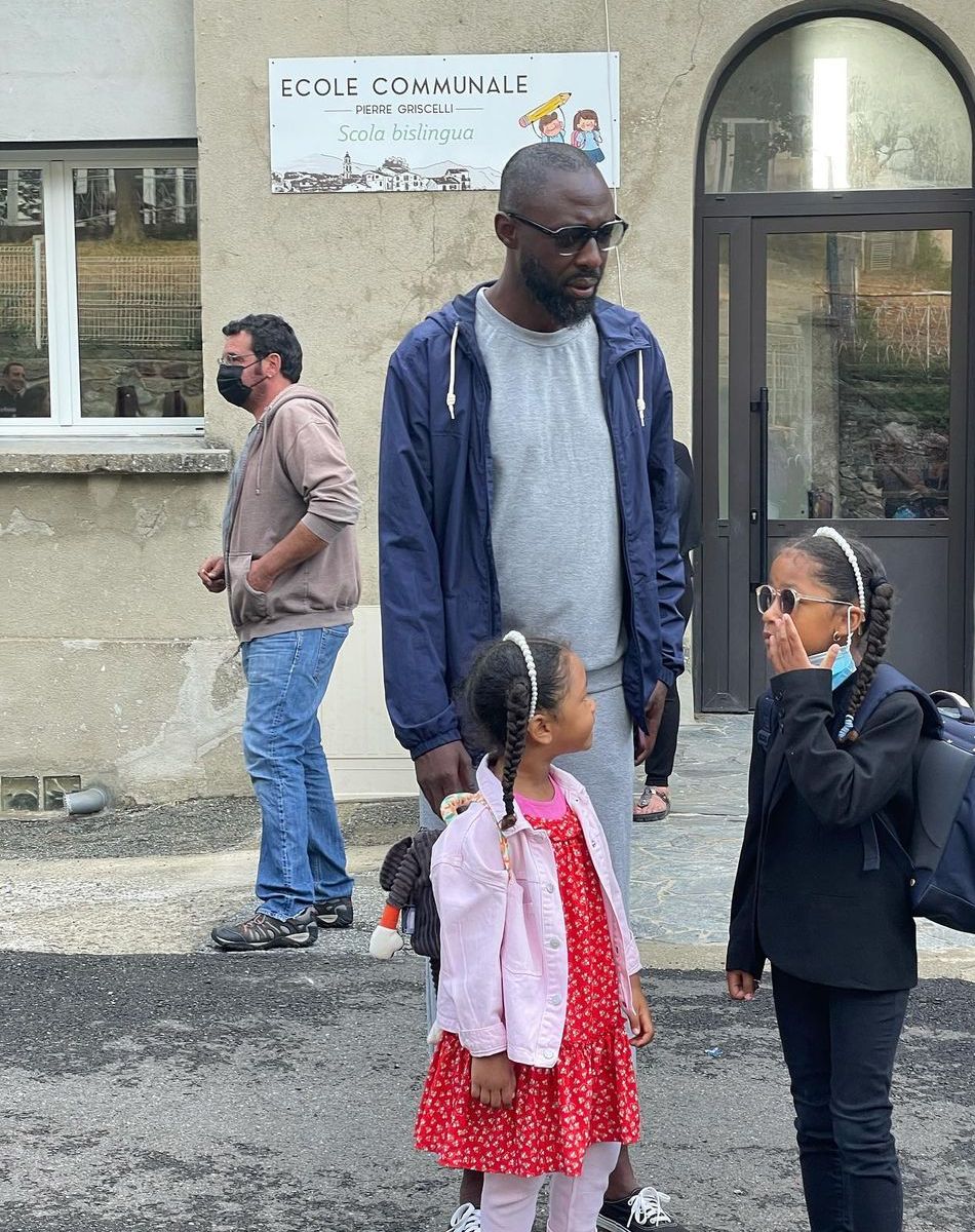 Thomas Ngijol et ses filles Angelina et Carmen devant la porte de leur école bilingue, en Corse.