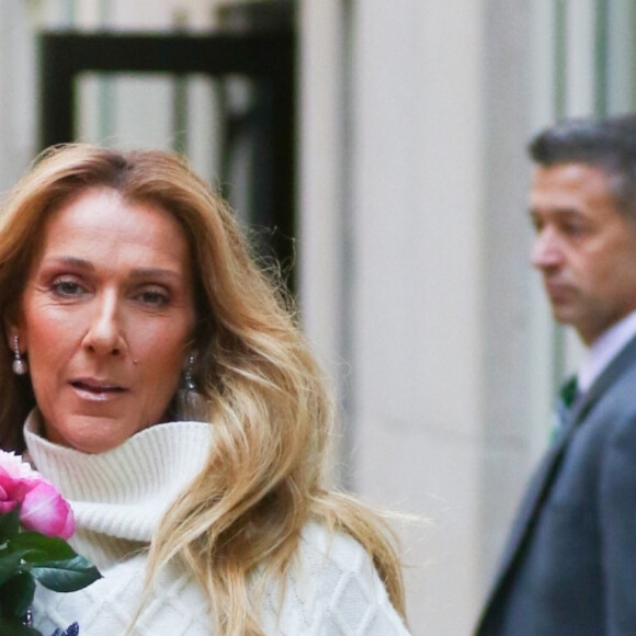 Celine Dion rayonnante et très souriante dans un ensemble pull écru et jupe bouffante fleurie salue ses fans à la sortie de son hôtel à New York, le 8 mars 2020 