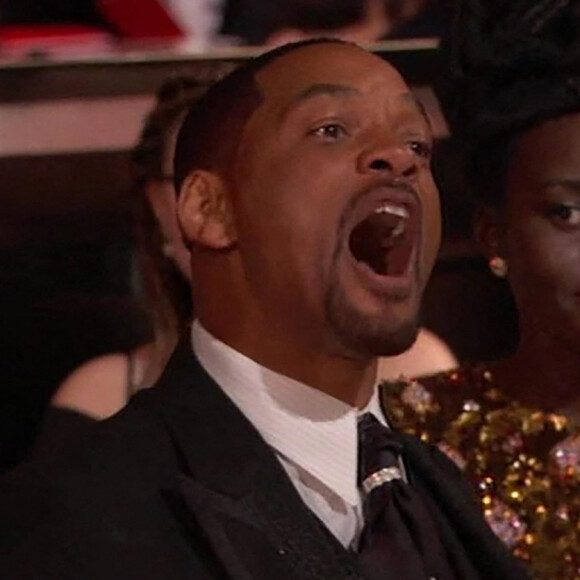 Will Smith insultant depuis son siège Chris Rock, après l'avoir violemment giflé. Il n'a pas supporté la blague que le comique a fait sur sa femme Jada Pinkett-Smith qui souffre d'alopécie. Derrière lui, l'actrice Lupita Nyong'o, témoin choquée de la scène. 27 mars 2022 - Los Angeles