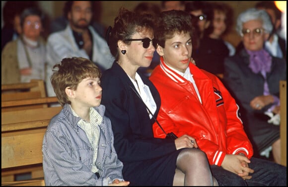 Marius et Romain Colucci avec leur mère Véronique lors de l'enterrement de Coluche en 1986