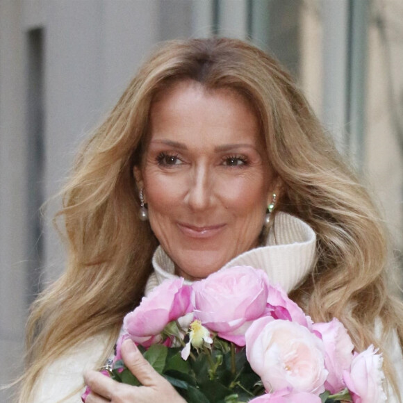 Celine Dion rayonnante et très souriante dans un ensemble pull écru et jupe bouffante fleurie salue ses fans à la sortie de son hôtel à New York, le 8 mars 2020 