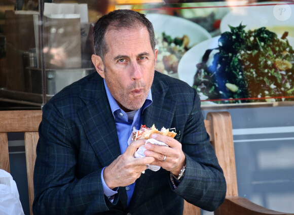Jerry Seinfeld mange un sandwich assis sur un banc à New York le 17 octobre 2018.