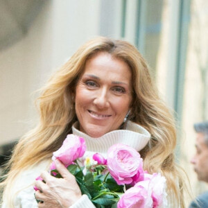 Céline Dion rayonnante et très souriante dans un ensemble pull écru et jupe bouffante fleurie salue ses fans à la sortie de son hôtel à New York, le 8 mars 2020
