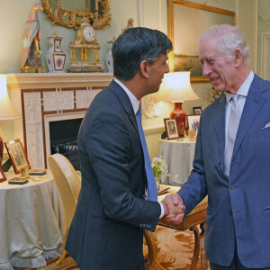 Par les messages de soutien et les cartes qu'il a reçus.
Le roi Charles III d'Angleterre, rencontre le Premier ministre britannique Rishi Sunak pour sa première audience en personne depuis le diagnostic de cancer du roi, au palais de Buckingham, à Londres, Royaume-Uni, le 21 février 2024. 