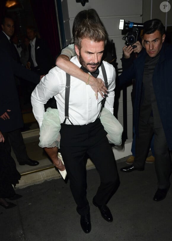 David Beckham porte sa femme Victoria Beckham sur son dos, à la sortie de la soirée de son 50ème anniversaire au club Oswald's à Londres, le 20 avril 2024. Arrivée munie de béquilles, Victoria Beckham a quitté sa fête d'anniversaire vers 2h30 du matin, portée par son mari depuis presque 25 ans.