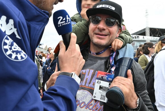 Michaël Youn avec son fils Stellar sur les épaules, en interview avec Vincent Cerutti lors des "24H du Mans 2024", le 15 juin 2024.