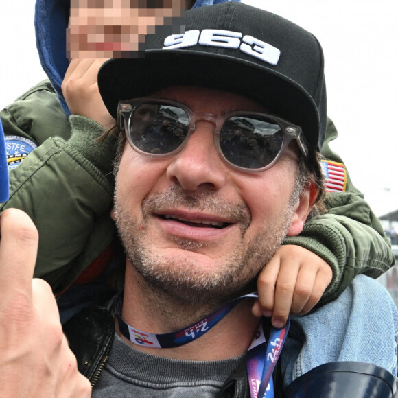 Michaël Youn avec son fils Stellar sur les épaules, en interview avec Vincent Cerutti lors des "24H du Mans 2024", le 15 juin 2024.