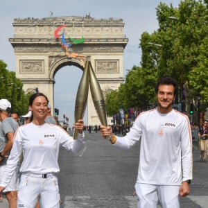 Amir et Nina Métayer lors du relais de la Flamme Olympique sur les Champs-Elysées à Paris, le 15 juillet 2024. 