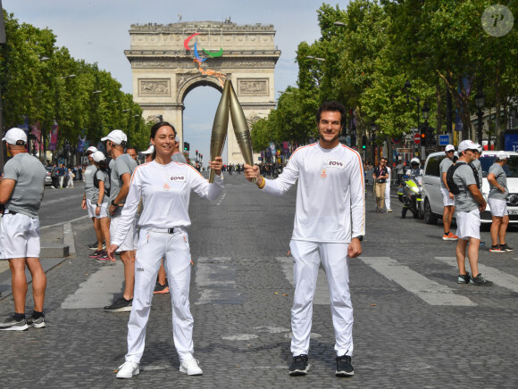 Amir et Nina Métayer lors du relais de la Flamme Olympique sur les Champs-Elysées à Paris, le 15 juillet 2024. 