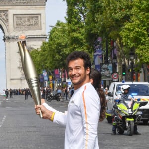 Amir et Nina Métayer lors du relais de la Flamme Olympique sur les Champs-Elysées à Paris, le 15 juillet 2024. 