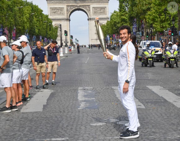 Amir et Nina Métayer lors du relais de la Flamme Olympique sur les Champs-Elysées à Paris, le 15 juillet 2024. 