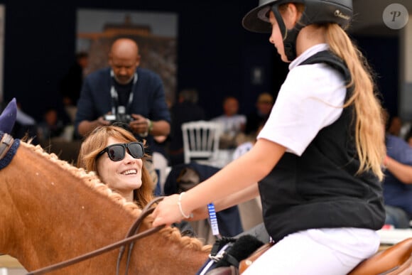 Carla Bruni Sarkozy et sa fille Giulia pendant l'épreuve Kids Cup L'Envol lors de la 10ème édition du "Longines Paris Eiffel Jumping" à la Plaine de Jeux de Bagatelle à Paris, France, le 21 juin 2024. © Perusseau-Veeren/Bestimage 