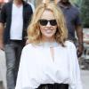 La chanteuse Kylie Minogue très chic et estival dans une petite robe blanche façon tunique, joliment rehaussée d'une large ceinture noire, portée avec de ravissantes sandales argentées et une paire de Ray-Ban sur le nez.