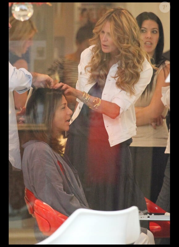 Elle Macpherson conseille une amie chez le coiffeur à Miami avec une amie. Juin 2011