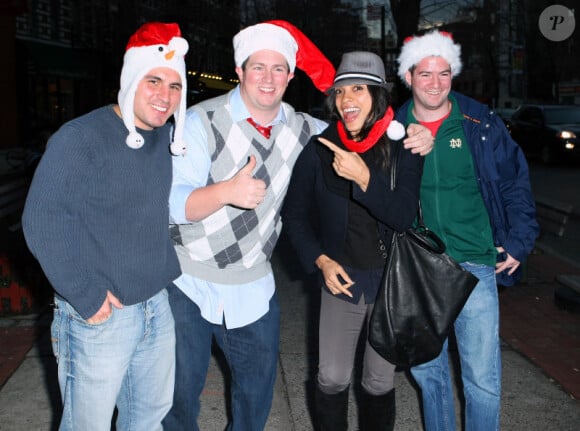 Rosario Dawson sort d'un restaurant à New York et prend la pose aux côtés de passants déguisés en Père Noël le 23 décembre 2011