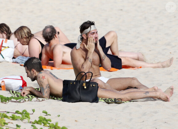 Le créateur Marc Jacobs, plongé dans ses lectures pendant que Lorenzo Martone se passe de la crème solaire. A Saint Barthélémy, le 28 décembre 2011.