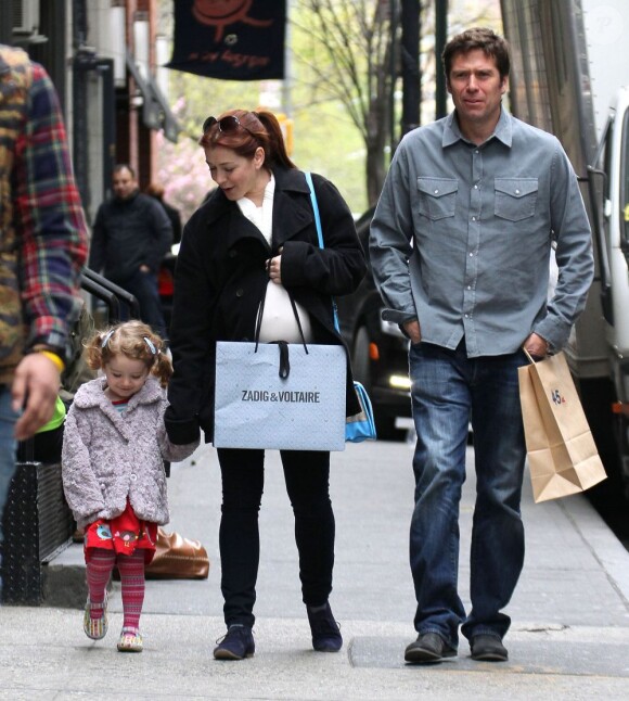 Essayant de cacher son ventre, Alyson Hannigan se promène avec son mari Alexis Denisof et leur fille Satyana à New York le 10 avril 2012