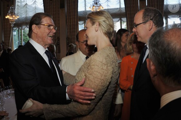 Albert et Charlene de Monaco saluent Roger Moore au dîner du Club des Ambassadeurs, organisé à l'Hôtel de Paris à Monaco, le 12 juin 2012.