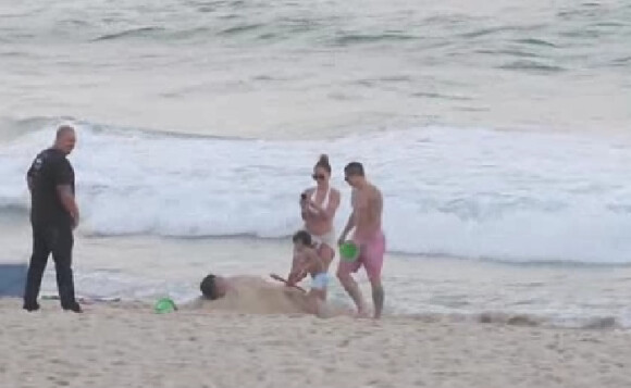 Jennifer Lopez filme ses jumeaux Max et Emme qui enterrent leur garde du corps sur une plage de Rio de Janeiro, le 25 juin 2012.