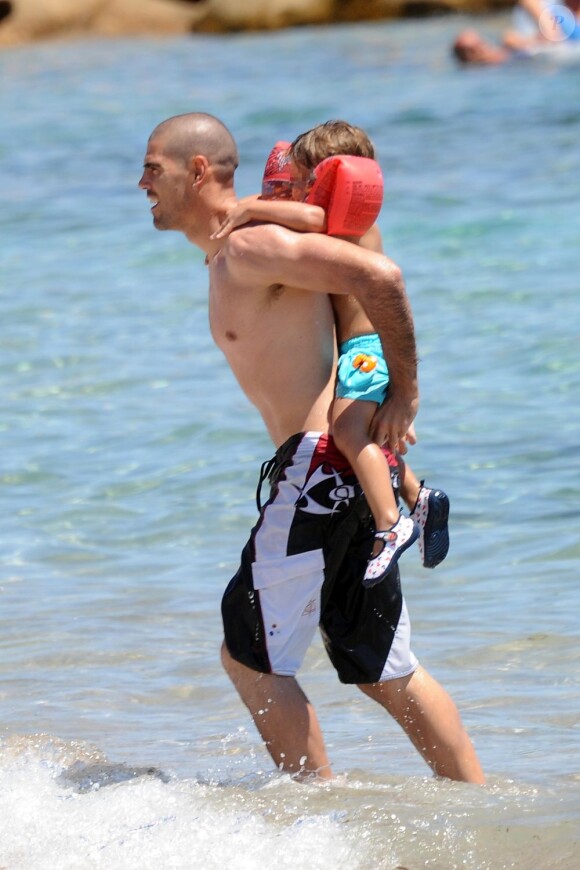 Victor Valdés et son petit Dylan en sortant de l'eau sur la plage de Sardaigne le 19 juillet 2012