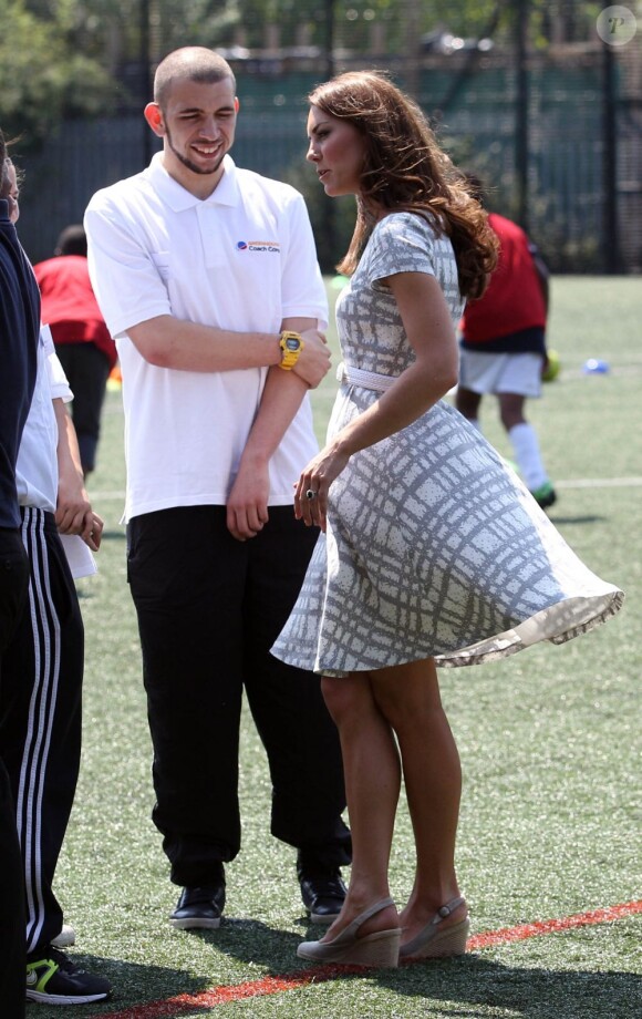 Attention aux coups de vent ! Kate Middleton, le prince William et le prince Harry, ambassadeurs de la Team GB pour les JO de Londres 2012, inauguraient ensemble le projet de formation de coachs Coach Core, le 26 juillet 2012 au Bacon College de Rotherhithe (sud-est de Londres).