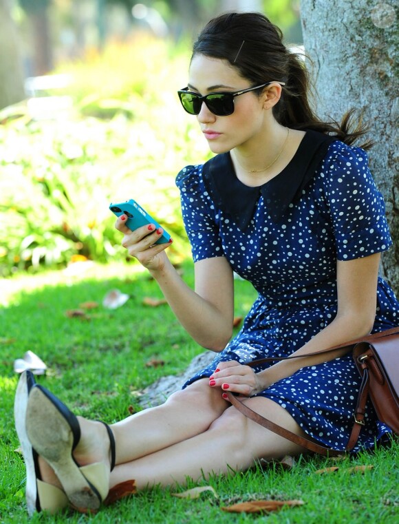 Absorbée par son iPhone, Emmy Rossum passe du bon temps dans un parc de Los Angeles. Le 15 août 2012
