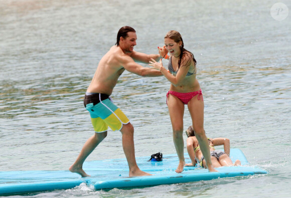 Peter Facinelli s'amuse à poussé son aînée Luca à l'eau pendant que Lola et Fiona tentent de grimper sur la planche, à Honolulu, Hawaï, le 31 août 2012