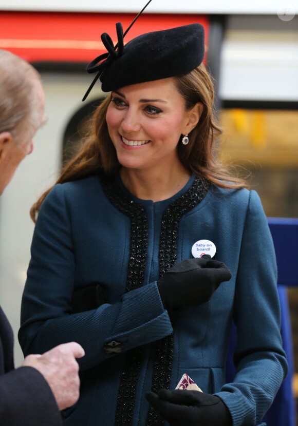Kate Middleton, duchesse de Cambridge, avec son badge 'bébé à bord', en visite à la station de métro de Baker Street avec la reine Elizabeth II et le duc d'Edimbourg, le 20 mars 2013, pour les 150 ans du Tube de Londres.