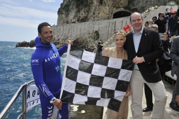 Le prince Albert de Monaco et son épouse Charlene prennent la posele vendredi 24 mai 2013 avec Pierre Frolla, parti chercher le drapeau à damier du Grand Prix de Monaco à 70 mètres de profondeur. Signés par les pilotes de F1, celui-ci sera vendu aux enchères au profit d'une association, Aequalia.