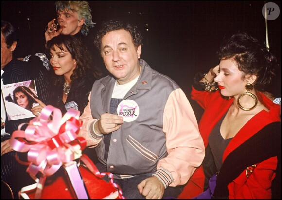Coluche lors d'une soirée à Paris le 13 décembre 1985 avec son badge des Restos du coeur