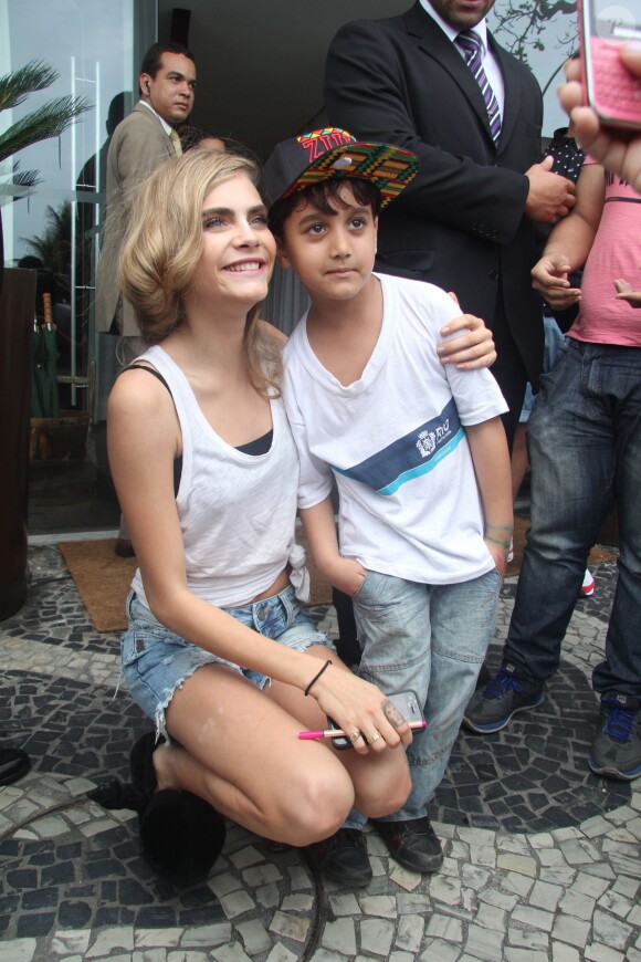 Cara Delevingne, star adorable avec un jeune fan devant l'hôtel Fasano à Rio de Janeiro. Le 3 octobre 2013.