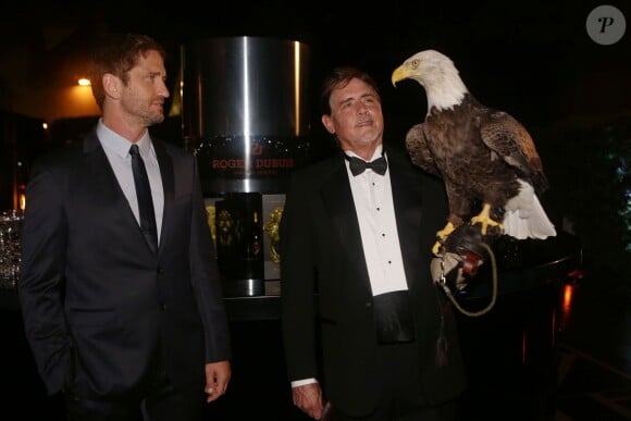 Gerard Butler et un fauconnier lors de la soirée privée Roger Dubuis célébrant le coup d'envoi d'Art Basel Miami Beach, à l'hôtel W South Beach. Miami, le 4 décembre 2013.