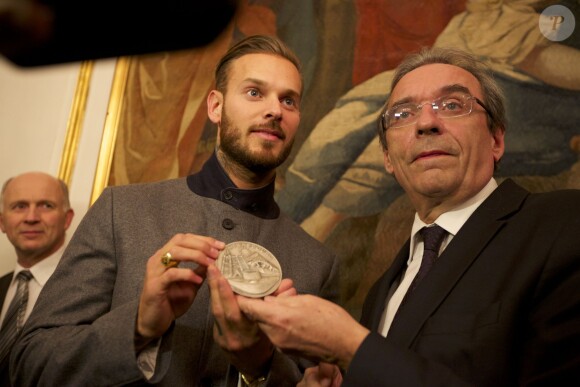 Le chanteur M. Pokora a reçu des mains du maire de Strasbourg Roland Ries la médaille d'honneur de la ville, lors d'une cérémonie organisée en présence de fans à l'hôtel de ville de Strasbourg, le 12 février 2014.