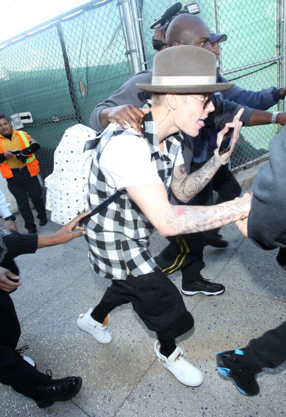 Justin Bieber quitte l'aéroport LAX de Los Angeles, entouré de ses gardes du corps et de la police, après avoir été retenu dans le bureau des douanes pendant 4 heures. Le 25 avril 2014.