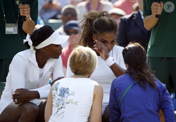 Serena Williams, en larmes avec les médecins du tournoi de Wimbledon, au côté de sa soeur Venus, après avoir été totalement désorientée et en perdition sur le court alors qu'elle disputait le double, le 1er juillet 2014
