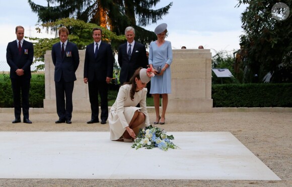 Kate Middleton, duchesse de Cambridge, dépose une gerbe de fleurs sous le regard des princes William et Harry, de David Cameron et du roi Philippe et de la reine Mathilde de Belgique au cimetière militaire Saint-Symphorien de Mons, en Belgique, le 4 août 2014 dans le cadre des commémorations du centenaire de la Première Guerre mondiale.