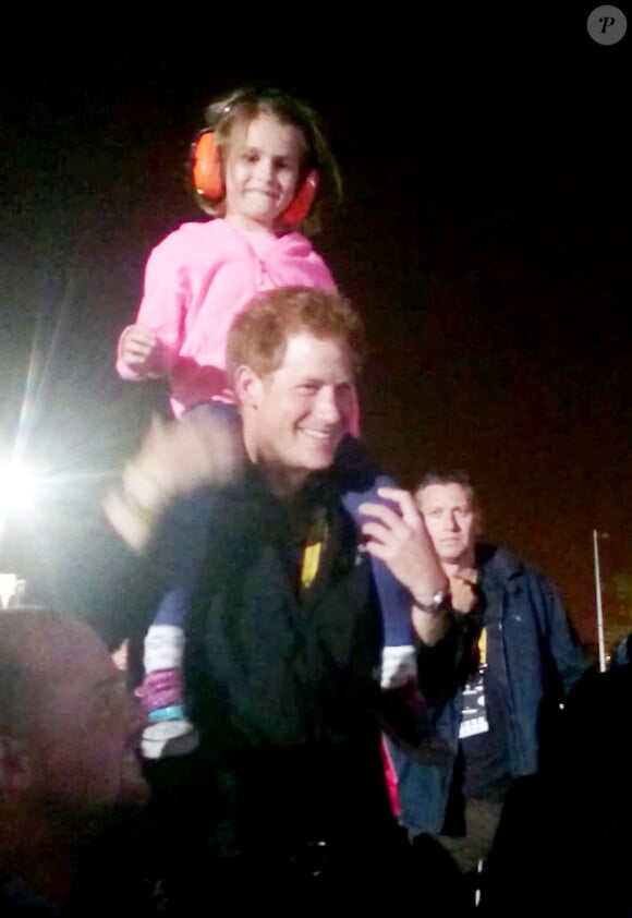Le prince Harry avec la petite Isabelle Nixon sur ses épaules pendant le concert des Foo Fighters lors de la clôture des Invictus Games, le 14 septembre 2014 à Londres.
