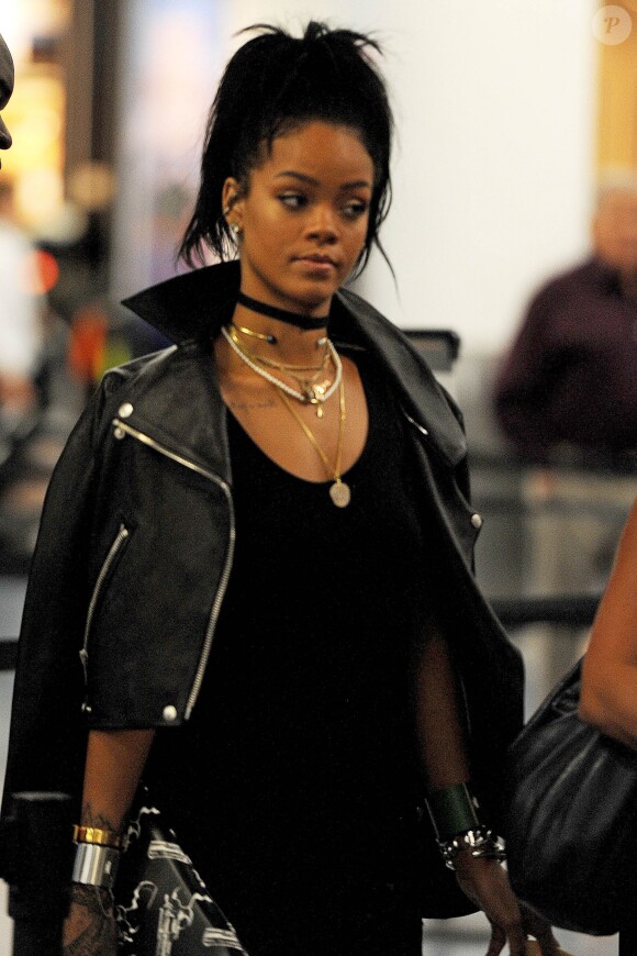 Rihanna (blouson Acne, pochette Saint Laurent) passe la douane et quitte l'aéroport de Miami. La star oublie d'enlever ses chaussures pour passer sous le détecteur. Le 9 octobre 2014 