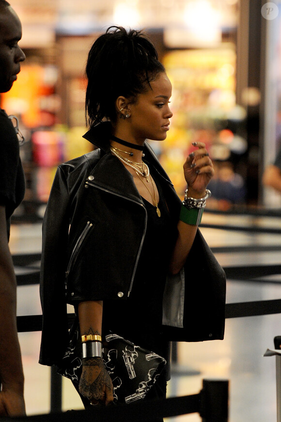 Rihanna (blouson Acne, pochette Saint Laurent) passe la douane et quitte l'aéroport de Miami. La star oublie d'enlever ses chaussures pour passer sous le détecteur. Le 9 octobre 2014  