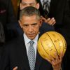 Barack Obama se voit remettre un ballon doré de la part des Spurs de Tony Parker et Boris Diaw, invités à la Maison Blanche à Washington, le 12 janvier 2015, suite à leur titre de champion NBA 2014