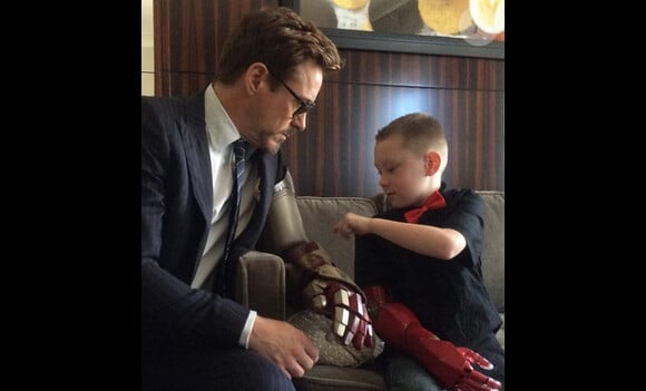 Photo de la rencontre entre Robert Downey Jr et Alex, 7 ans, à qui la star offre un bras bionique.