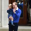 Le prince George de Cambridge dans les bras de son père William pour aller découvrir sa petite soeur la princesse Charlotte à la maternité Lindo, le 2 mai 2015, à Londres